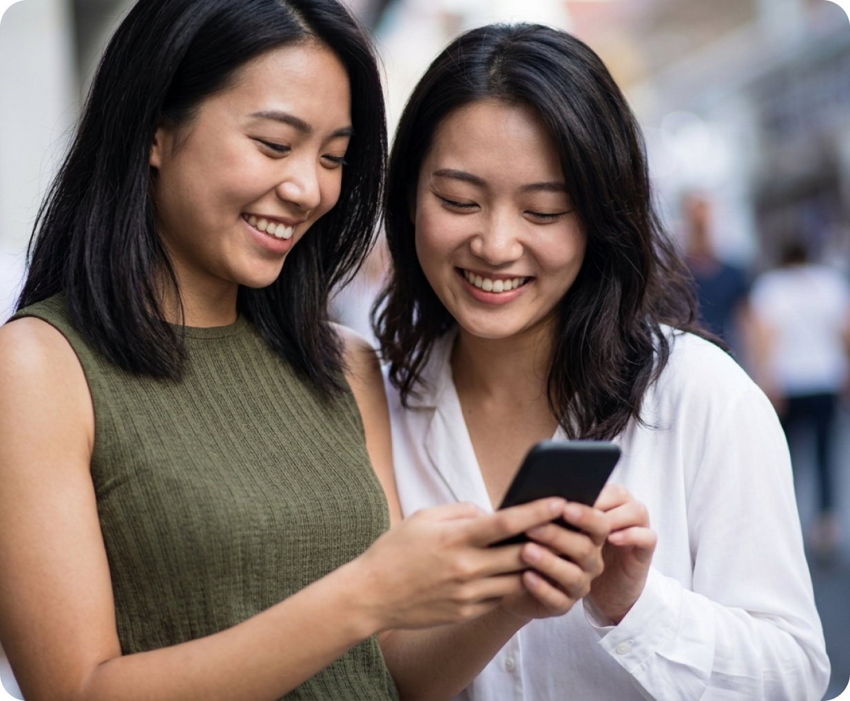 Two women smiling while looking at a phone together